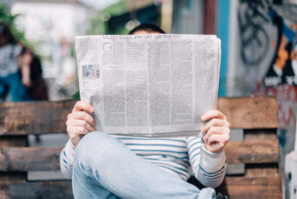 Picture of a person reading a newspaper learning about local Raleigh businesses